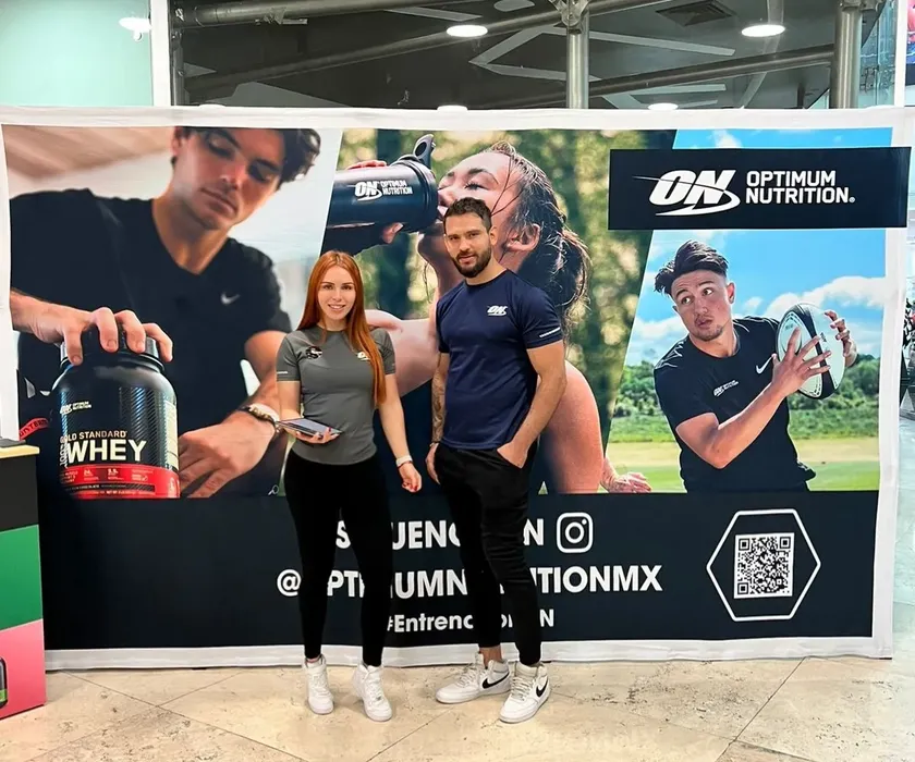 Grupo de personas y promotores en stand de nutrición y suplementos deportivos de la agencia.